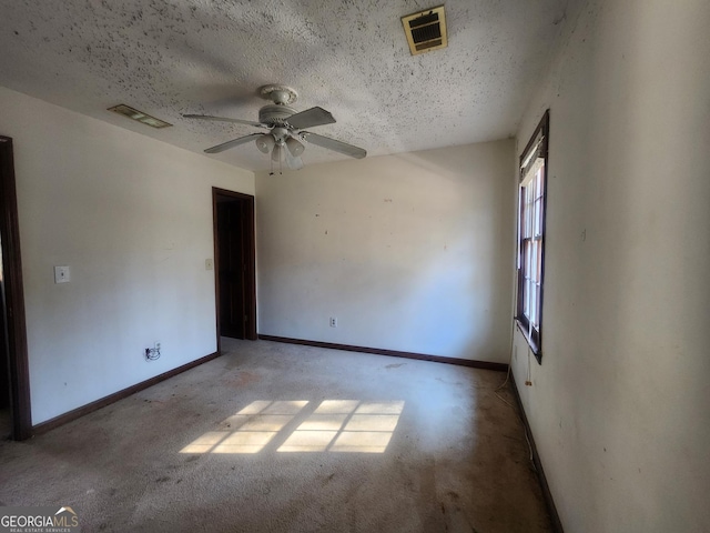 spare room with ceiling fan, light colored carpet, and a textured ceiling