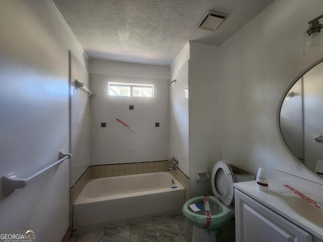 full bathroom with tiled shower / bath, vanity, toilet, and a textured ceiling