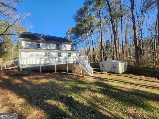 back of property with a storage shed, a yard, and a deck