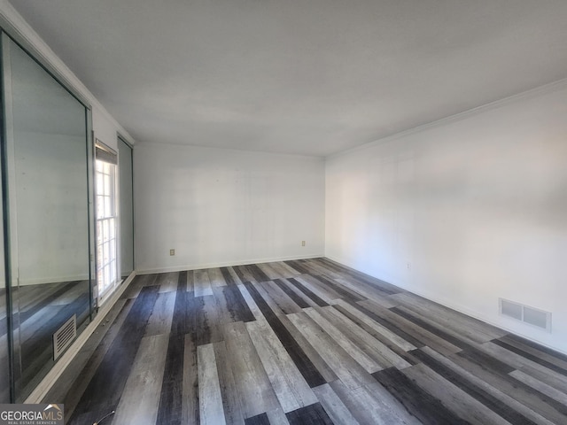 empty room with dark hardwood / wood-style flooring and ornamental molding