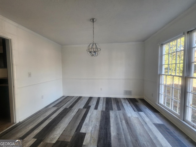 unfurnished dining area featuring dark wood-type flooring, crown molding, and an inviting chandelier