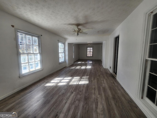 unfurnished living room featuring dark hardwood / wood-style flooring, ceiling fan, and a textured ceiling