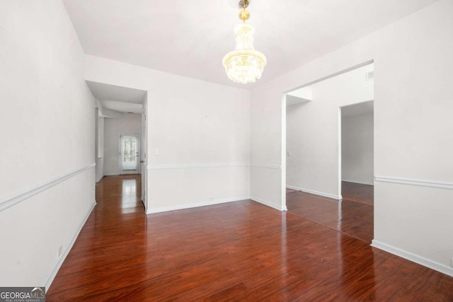 unfurnished room featuring dark hardwood / wood-style floors and a notable chandelier