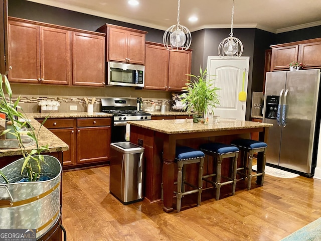 1320 Newbridge Cir, Buford, GA 30519 - kitchen with stainless steel appliances, a kitchen island, light wood-type flooring, a breakfast bar, and crown molding