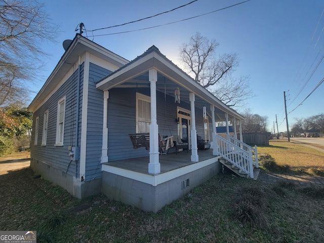 view of side of property featuring a porch and a lawn