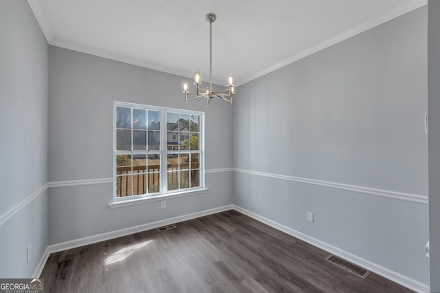 spare room featuring dark wood-type flooring, ornamental molding, and a chandelier