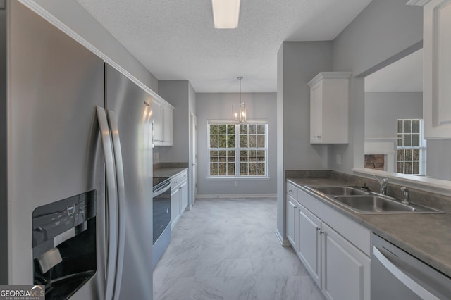 kitchen featuring appliances with stainless steel finishes, sink, pendant lighting, and white cabinets