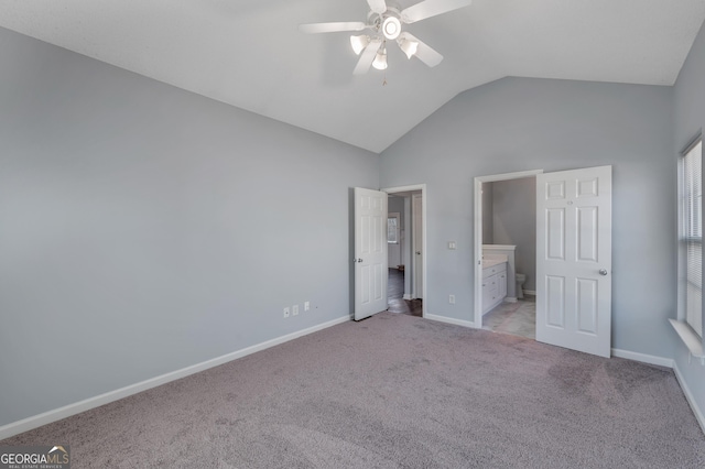 unfurnished bedroom featuring lofted ceiling, ensuite bath, light colored carpet, and ceiling fan