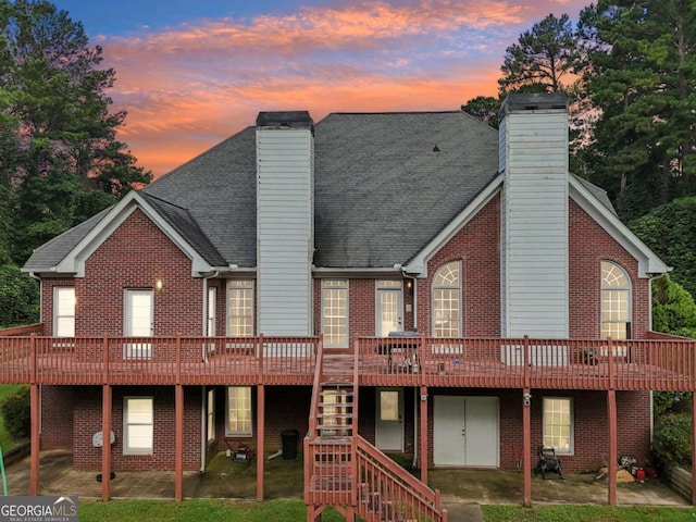 back house at dusk featuring a wooden deck and a yard