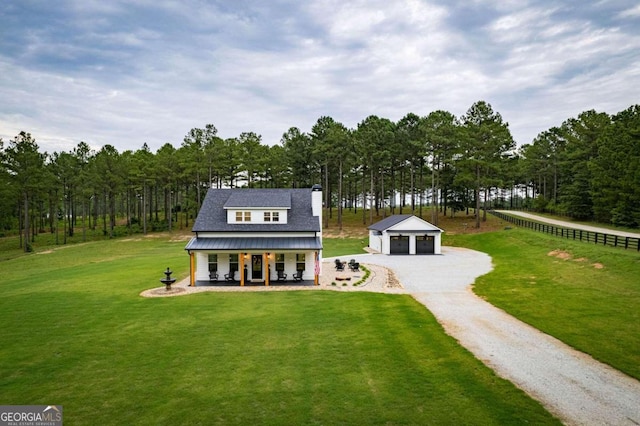 view of front facade featuring a porch, a garage, an outbuilding, and a front lawn