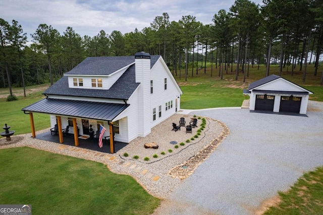 view of side of property with a garage, a yard, an outbuilding, and covered porch