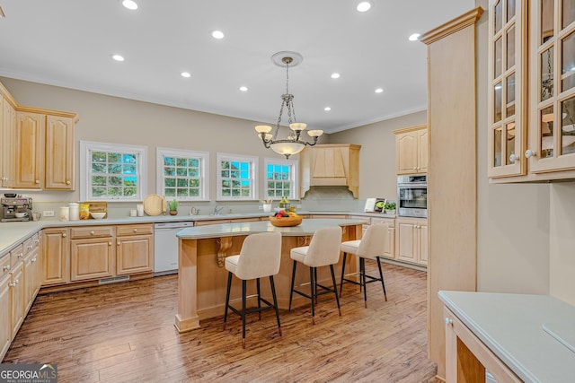 kitchen with a kitchen island, light brown cabinetry, oven, hanging light fixtures, and white dishwasher