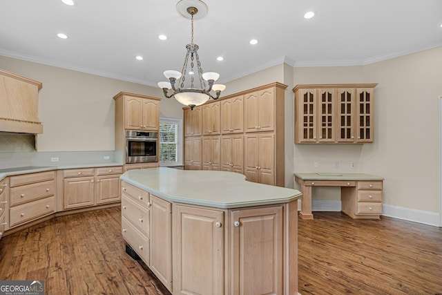 kitchen featuring light brown cabinetry, decorative light fixtures, a center island, and stainless steel oven