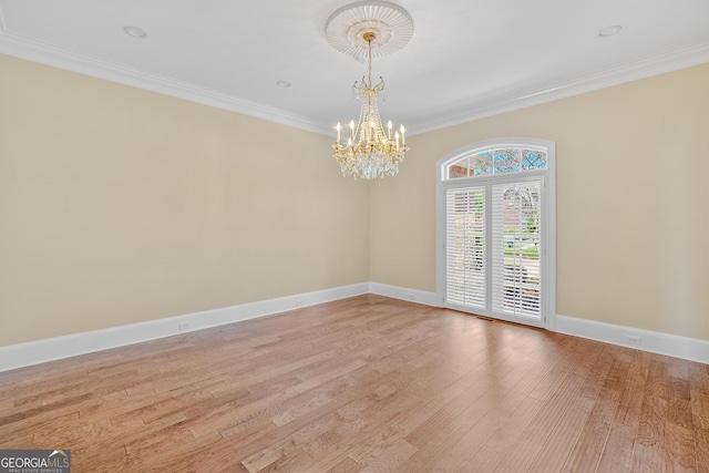 spare room with crown molding, light hardwood / wood-style floors, and a notable chandelier