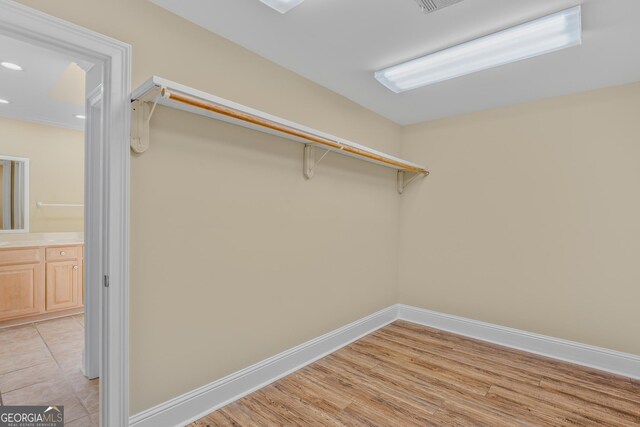 walk in closet with light hardwood / wood-style flooring