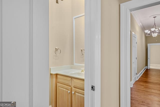 bathroom featuring vanity, ornamental molding, wood-type flooring, and a chandelier