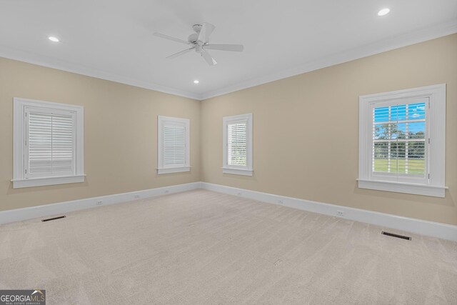 carpeted empty room with ceiling fan, a healthy amount of sunlight, and ornamental molding