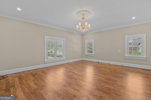 empty room featuring an inviting chandelier, crown molding, and light hardwood / wood-style flooring