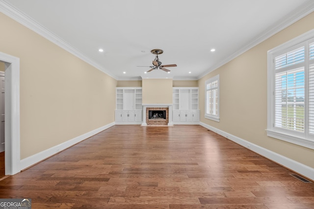 unfurnished living room featuring crown molding, ceiling fan, wood-type flooring, and built in shelves