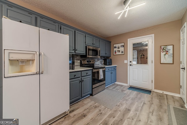 kitchen featuring tasteful backsplash, appliances with stainless steel finishes, light hardwood / wood-style floors, and a textured ceiling