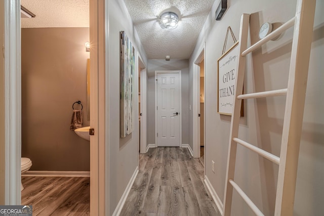 hall featuring light hardwood / wood-style floors and a textured ceiling