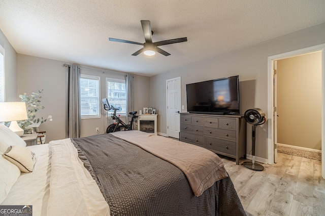 bedroom featuring ceiling fan, light hardwood / wood-style floors, and a textured ceiling