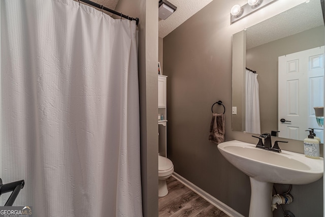 bathroom with wood-type flooring, a textured ceiling, and toilet