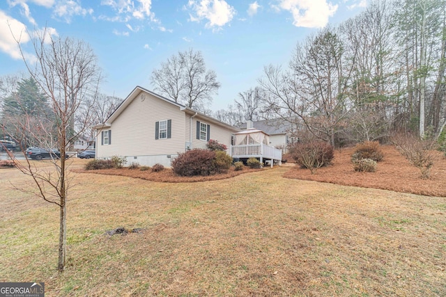 view of home's exterior with a wooden deck, a yard, and a sunroom