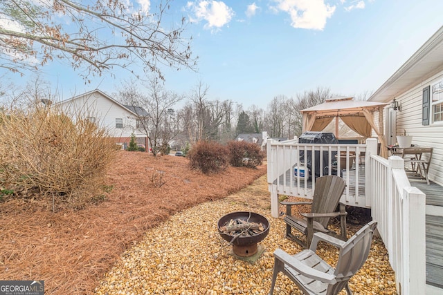 view of yard with a gazebo, a wooden deck, and a fire pit