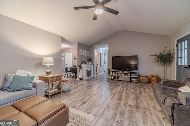 living room with lofted ceiling, ceiling fan, and light hardwood / wood-style flooring