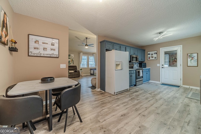 kitchen featuring blue cabinetry, appliances with stainless steel finishes, light hardwood / wood-style floors, and a textured ceiling