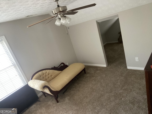 sitting room with ceiling fan, dark carpet, vaulted ceiling, and a textured ceiling