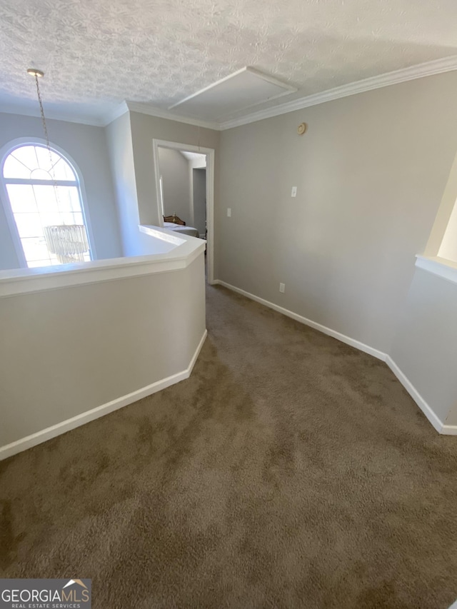 spare room with ornamental molding, a textured ceiling, and dark colored carpet