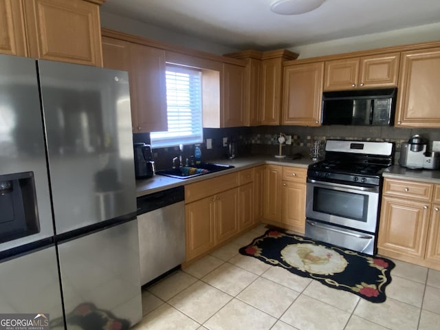 kitchen featuring light tile patterned floors, appliances with stainless steel finishes, sink, and backsplash