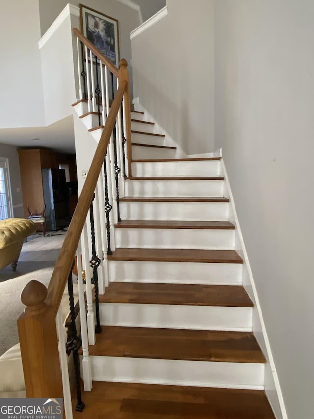 stairs featuring hardwood / wood-style floors and a towering ceiling