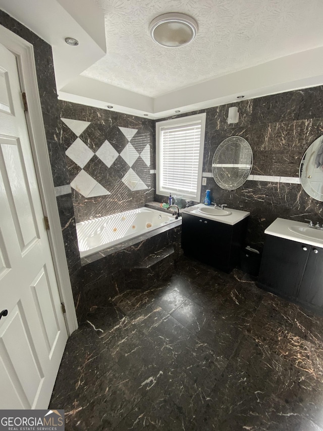 bathroom with vanity, tile walls, tiled bath, and a textured ceiling