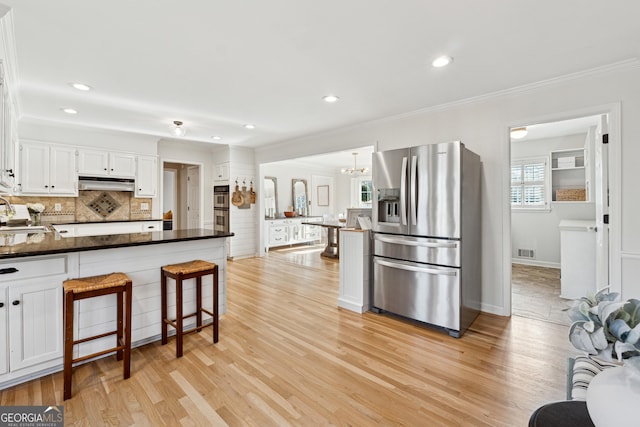 kitchen with backsplash, stainless steel appliances, light wood-type flooring, and white cabinets