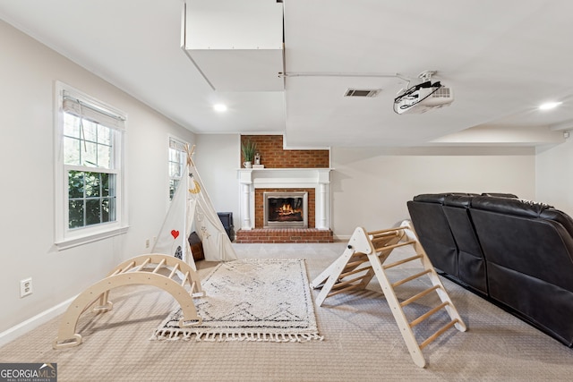 recreation room with a brick fireplace and carpet flooring