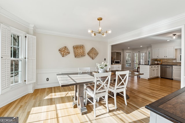 dining space featuring crown molding, light wood-type flooring, and a notable chandelier