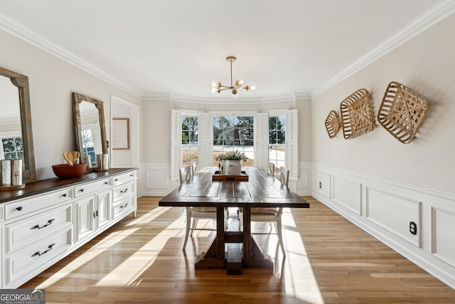 dining space featuring a notable chandelier, ornamental molding, and light wood-type flooring