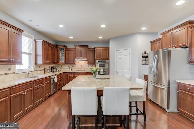 kitchen with a breakfast bar, sink, decorative backsplash, a center island, and stainless steel appliances