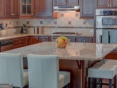 kitchen featuring backsplash, light stone countertops, and a kitchen bar