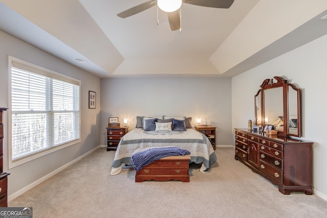 carpeted bedroom with a raised ceiling and ceiling fan