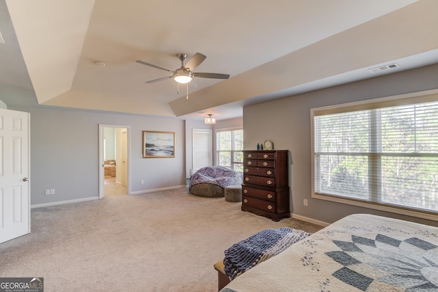 carpeted bedroom with ceiling fan, ensuite bathroom, and a tray ceiling