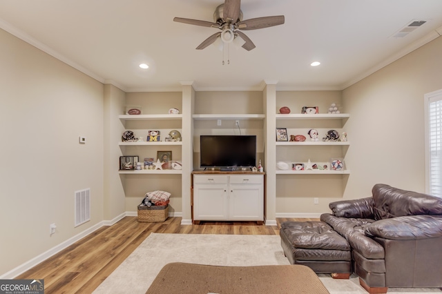 living room featuring ornamental molding, ceiling fan, light wood-type flooring, and built in shelves