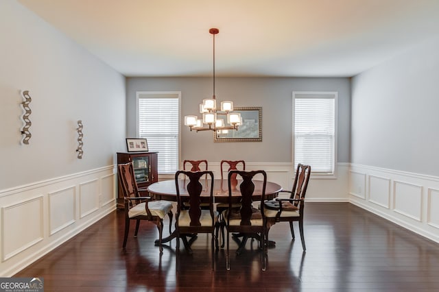 dining space with a healthy amount of sunlight, an inviting chandelier, and dark hardwood / wood-style flooring