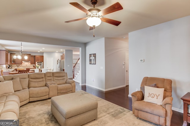 living room featuring ceiling fan with notable chandelier and wood-type flooring