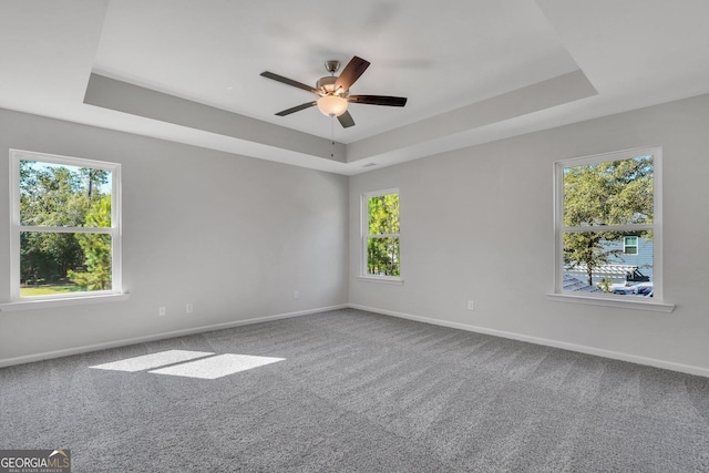 carpeted empty room featuring a raised ceiling and ceiling fan