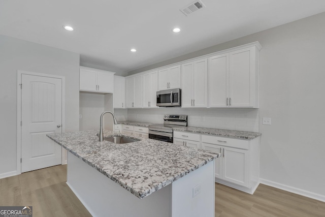 kitchen with an island with sink, stainless steel appliances, sink, and white cabinets