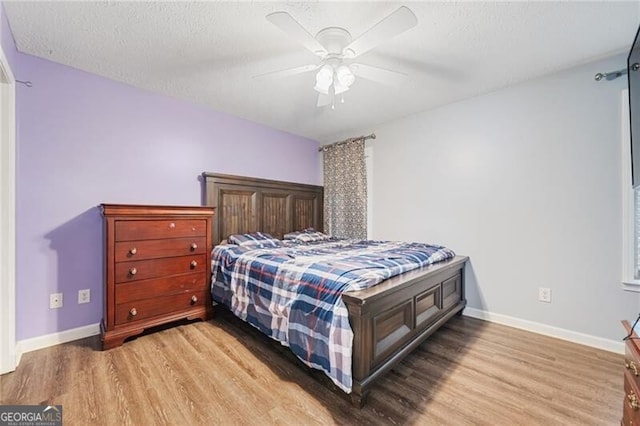 bedroom featuring ceiling fan, light hardwood / wood-style flooring, and a textured ceiling